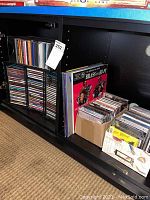 Shelf with multiple music CDs, some in cases, some in paper sleeves and a box holding many CDs.