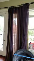 Curtain panel partially covering glass door with view outside.