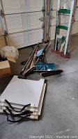 Yard tools including shovels, rakes, snow shovels, push broom, hand truck, and white boards.