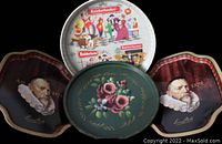 Group photo showing a round Knickerbocker tray with multiple illustrated scenes, a green floral painted tray, and two dark portrait-shaped trays