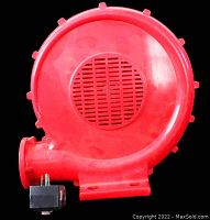 Front view of red plastic bounce house blower showing air intake grill and electrical plug.