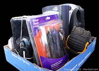 Photo of box containing handheld spotlight, camera case in packaging, battery pack, headlamp with strap, and other small electronics