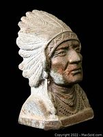 Front angle showcasing the facial features and feather headdress of the coin bank