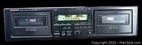 Front view of ONKYO stereo cassette double deck tape deck showing two cassette compartments closed and illuminated playback display with controls.