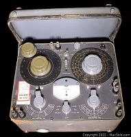 Top view of the impedance bridge showing control dials, meter, switches, and labels on a metal surface with open lid