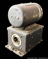 Angled side view showing metal housing, red painted markings, wear and paint chipping on black metal cylindrical dynamotor.