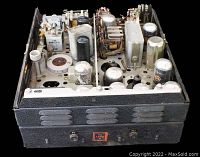 Open view of the radio unit showing vacuum tubes, capacitors, and other electronic components inside the metal chassis.