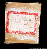 Photo shows front of the aged cardboard box with red bordered label and faded text.