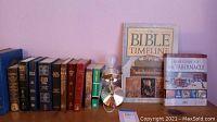 View of multiple Bibles lined up, Bible Timeline book, Rose Guide to the Tabernacle, and metallic lamp with light bulb.