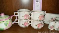 Photo showing four floral soup bowls with pink rose pattern and two salt and pepper shakers placed on a wooden shelf
