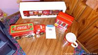 Full lot view showing Coca Cola truck, two firetrucks, two tin boxes, and mug.