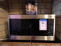 Front view of Panasonic microwave oven showing stainless steel exterior, black glass door, and control panel on the right.