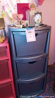 Blue plastic storage drawers with decorative items on top including plush bear, figurines, pins, and cards.
