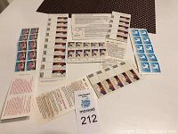 Overhead photo showing multiple stamp sheets and booklets spread out on a flat surface, featuring designs including an angel and a blue-themed stamp.