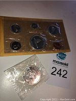 Full shot of the 1967 Canadian Centennial coin set in original yellow packaging alongside the separately packaged 1864-1964 Canadian silver dollar coin.