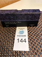 Photo of the front of the box showing the label 'Essential Oils', '100% Pure Essential Oils', and 'Top 6'. The box is black with purple floral designs.