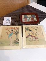 Two Japanese art pictures on rice paper with lace sides and one framed Japanese art print on a table.