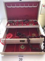 Jewelry box open showing multiple compartments with various vintage jewelry pieces including earrings, rings, bangles, and a brooch.