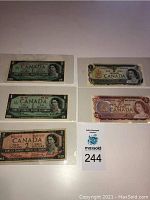 Top view of six different older Canadian banknotes, displaying front sides with Queen Elizabeth II portraits.