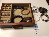 Photo of 10 rings and 10 bracelets in a beige fabric-lined compartment drawer organizer, showing jewelry variety and style.