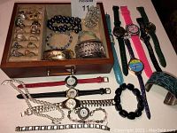 Full lot displayed including rings in a jewelry tray, bracelets beside the tray and watches and bracelets laid out on the table.