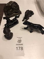 Overview photo of all five animal figurines and the wooden carved face grouped together on a white surface showing the variety and scale of each item.