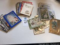 Collection of vintage cards and postcards scattered on a white surface. Multiple folded greeting cards and postcards visible.