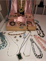 Overview photo showing necklaces draped on and around jewelry box, earrings and rings organized in compartments and arranged in front