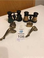 Full lot shown on table: two pairs of vintage opera glasses, two Japanese brass lighters, two brass decorative women's legs.