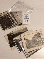 Photo showing several vintage postcards stacked and partly visible, featuring old buildings and scenic views in monochrome.