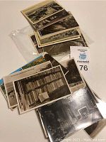Photo showing various vintage unmarked postcards stacked and fanned, highlighting photographic images of locations and buildings in black and white and sepia tones.