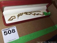 Full view of chain laid in red box with green 10K tag and MaxSold lot sticker