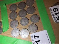 Twelve coin reverse sides arranged on cardboard, showing “50 CENTS” and wreath design.