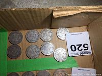 Eight Newfoundland 1919 fifty cent coins in a cardboard box showing circulation wear and bent edges on some coins.