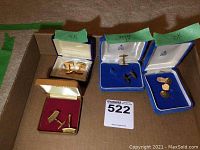 Three open cufflinks cases on flat surface showing 14K, unknown plated, and 10K gold pairs