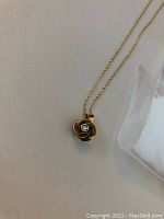 Front view of rose-shaped pendant with central diamond on chain