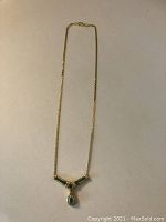 Full length view of necklace on flat surface showing chain and pendant