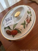 Top view of the oval casserole lid showing the gold knob and fruit pattern