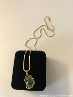 Nephrite jade pendant necklace draped over black display pad