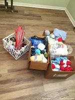 Overview photo of all boxes containing yarn, knitting needles, and projects on a wooden floor