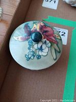 Top view of the decorative floral lid of the bowl showing the knob and flower details with visible crazing.