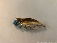 Front view showing cluster of ten round medium blue cabochon turquoise stones and two-tone gold leaf motif.