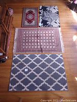 Overhead view of all four rugs laid out on wooden floor showing size and pattern differences