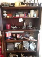 Overall view of wooden shelving with assorted decor items including candles, frames, boxes, figurines, and playing cards.