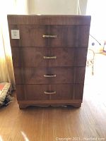 Front view of the wood 5-drawer deco dresser showing brass handles and visible wear near the base and edges.