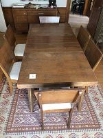 Rectangular wood dining table with two leaves installed, surrounded by chairs on southwestern rug