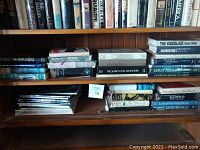 Shelf of assorted vintage hardcover books and magazines showing titles and condition.