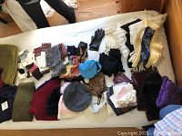 Full view of the assorted gloves, hats, scarves, socks, hosiery, and chair pads spread out on a white surface.