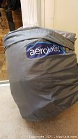 Gray carrying bag with Aerobed label visible, packed and zipped, indicating the product inside is an Aerobed mattress.