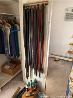 Leather belts hanging vertically with buckles at the top, various brown and black leather materials.